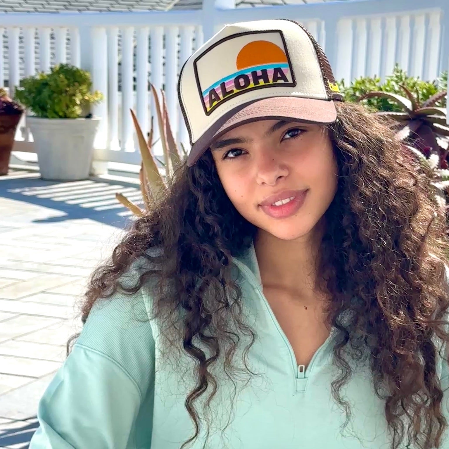 Brown Aloha Trucker Hat with embroidered sun and stripes worn by model