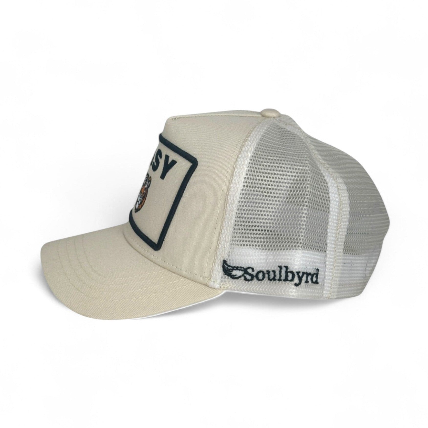 Cream Soulbyrd trucker hat side view with cotton twill front, mesh back, and wing logo