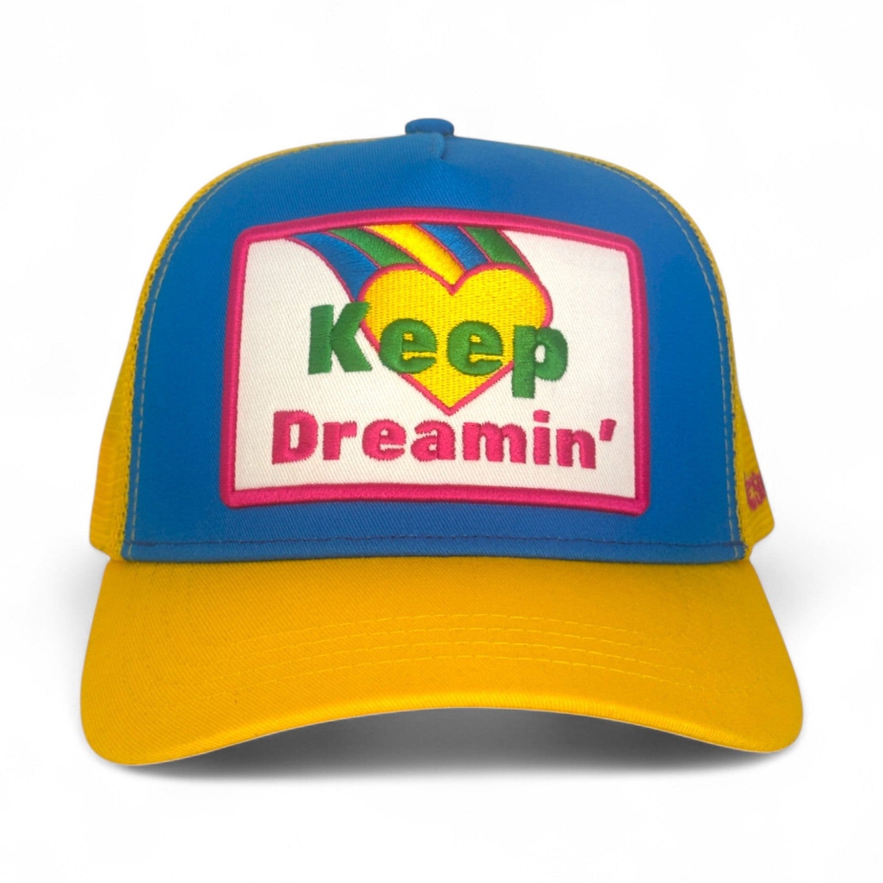 Blue and yellow trucker hat with embroidered Keep Dreamin' heart patch
