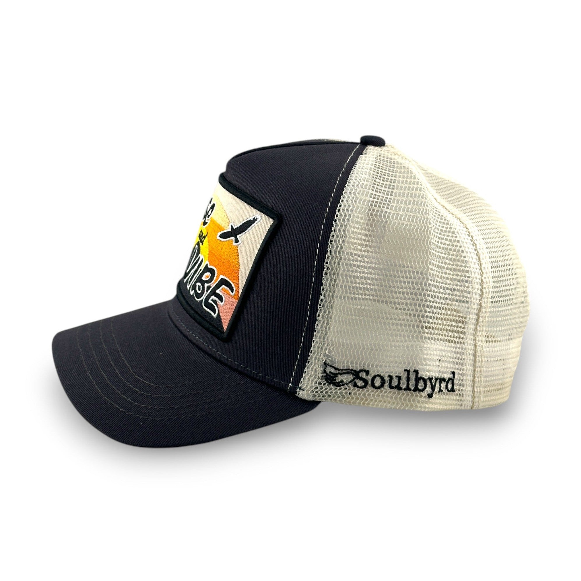 Charcoal cotton twill trucker hat side view showing beige mesh back and embroidered sunset patch