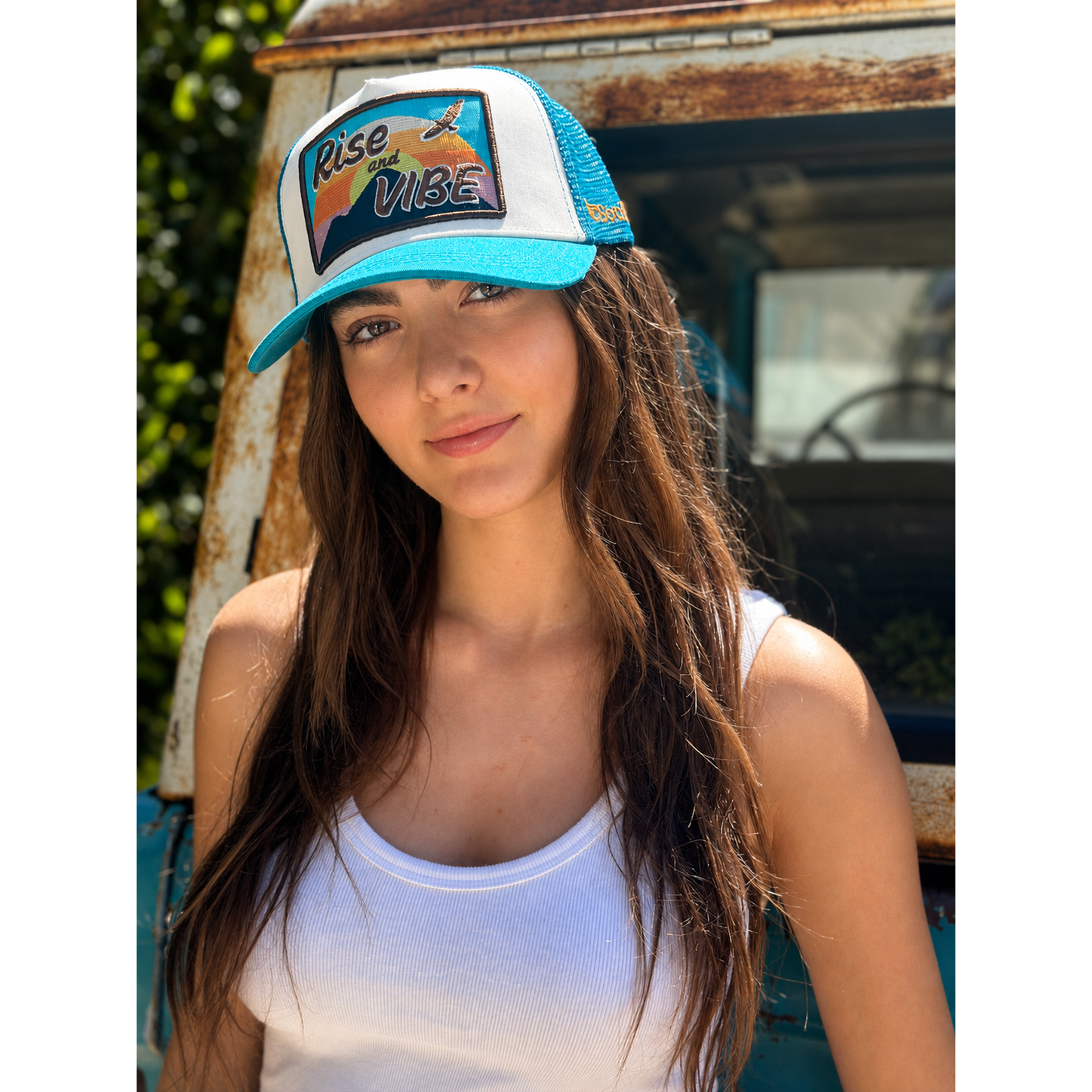 Woman wearing Rise & Vibe turquoise trucker hat with white front panel outdoors