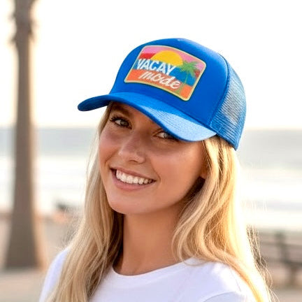 Model wearing blue adjustable trucker hat with beach vacation design outdoors