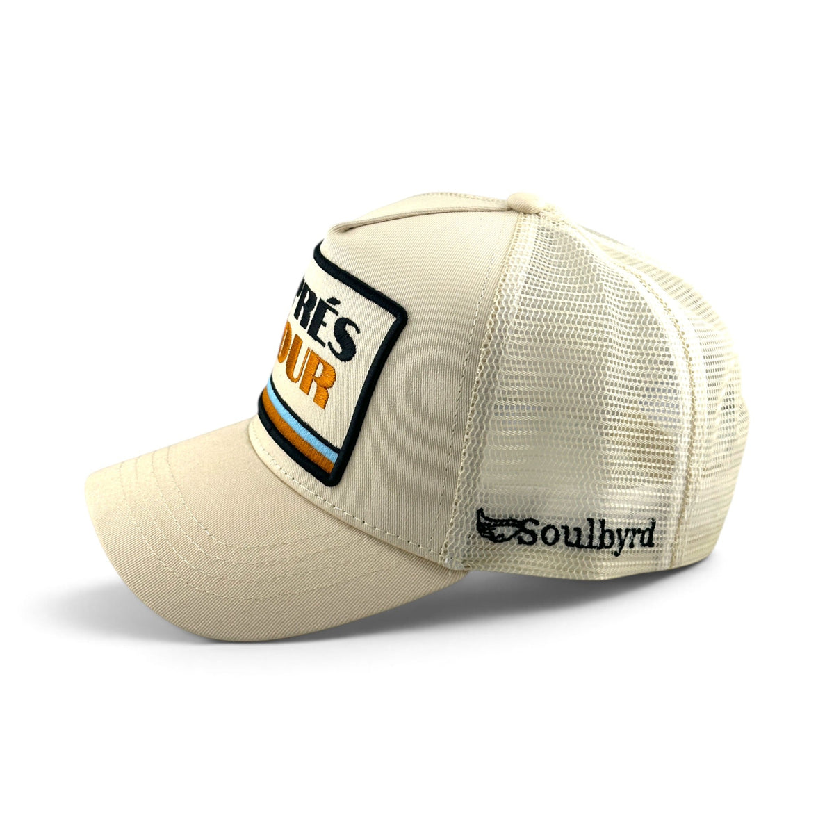 Soulbyrd Wholesale ivory 5-panel trucker hat with cotton twill front, nylon mesh back, and Aprés Hour patch detail.